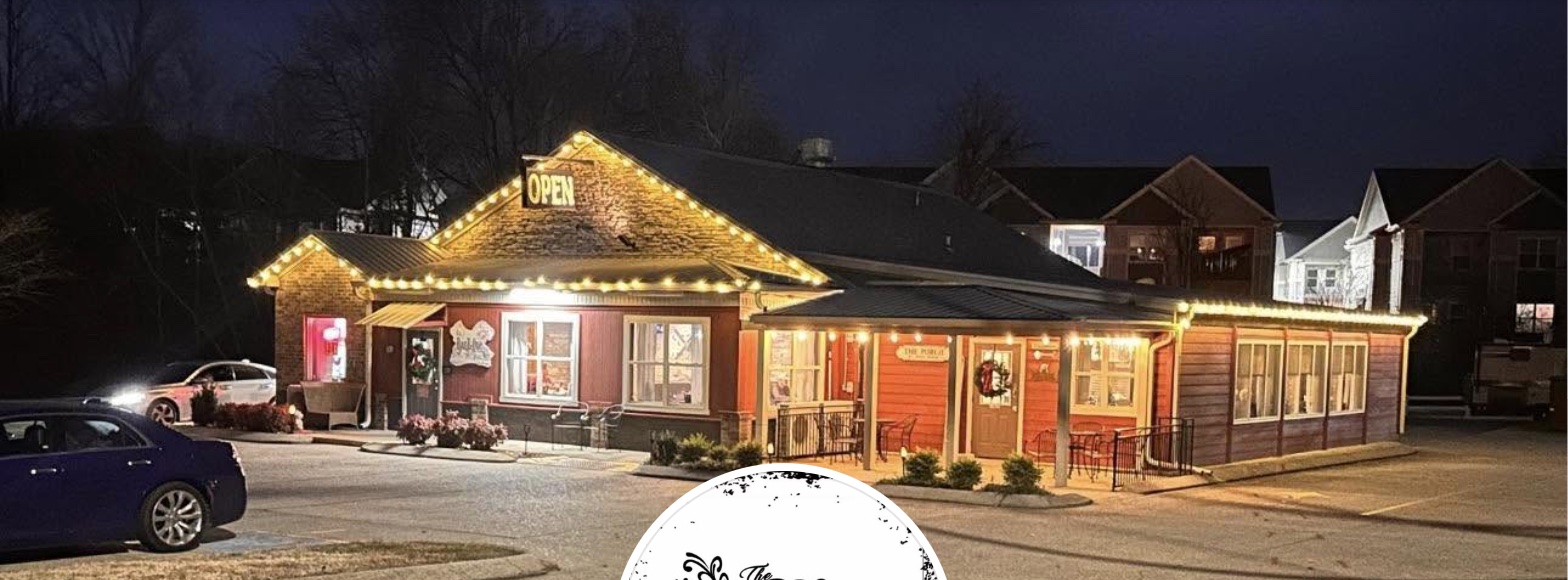 The BBQ Place Porch & Grill at night, its porch and roofline lit with warm string lights and an OPEN sign in the gable