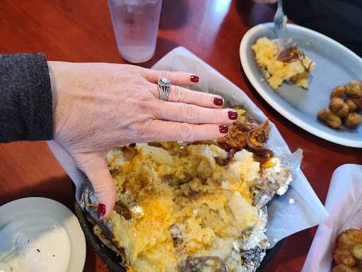 A loaded baked potato piled with smoked pulled pork, cheese and butter